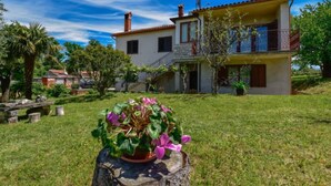A two-story house with a balcony, surrounded by a well-maintained lawn and trees. - Apartment Santin by Interhome (Umag/Savudrija)