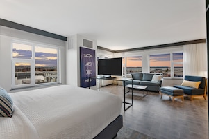 Una habitación de hotel moderna con una cama grande, un televisor de pantalla plana, un sofá y un escritorio.