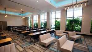 A conference room with tables, chairs, and a large window with a view of trees. - Hotel Indigo Everett - Waterfront Place by IHG (Everett)