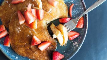 Una porción de tortitas con fresas y una cuchara.