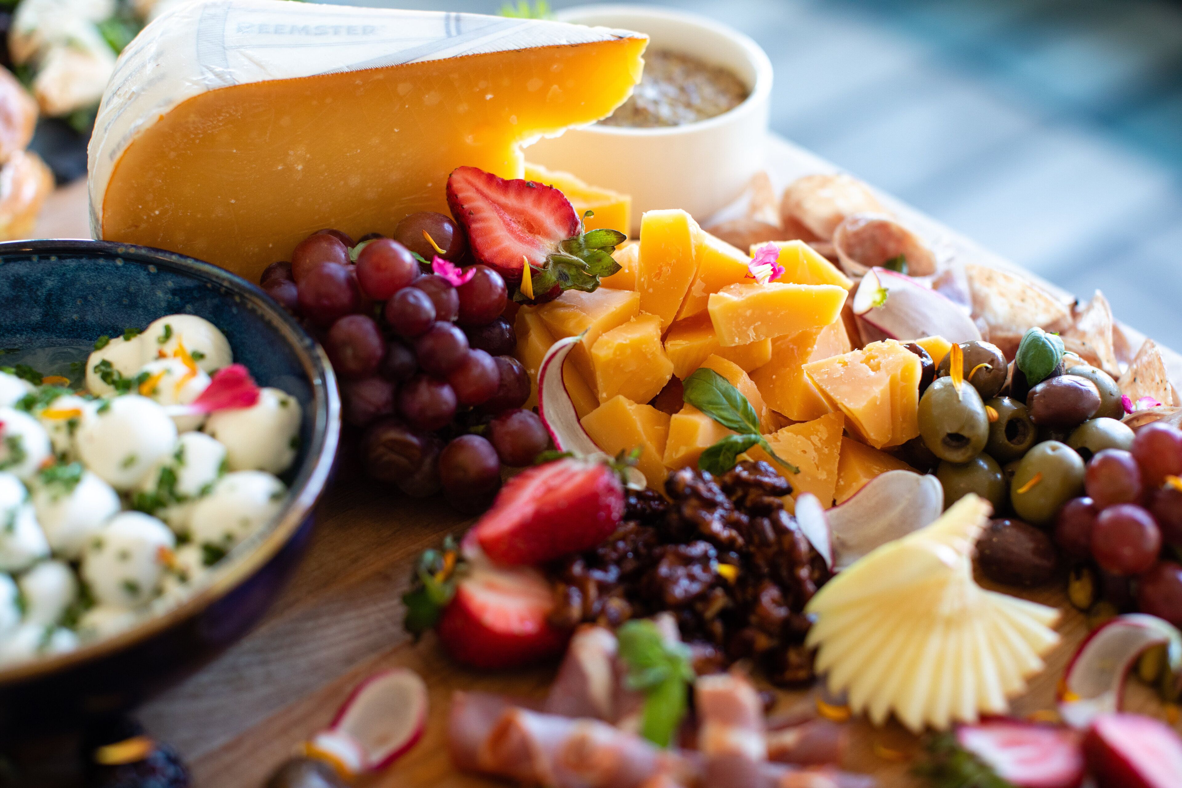 Une sélection de fromages, de fruits et de noix présentés sur une planche en bois.