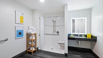A modern bathroom with a glass-enclosed shower, a wooden towel rack, a sink with a mirror, and a toilet.