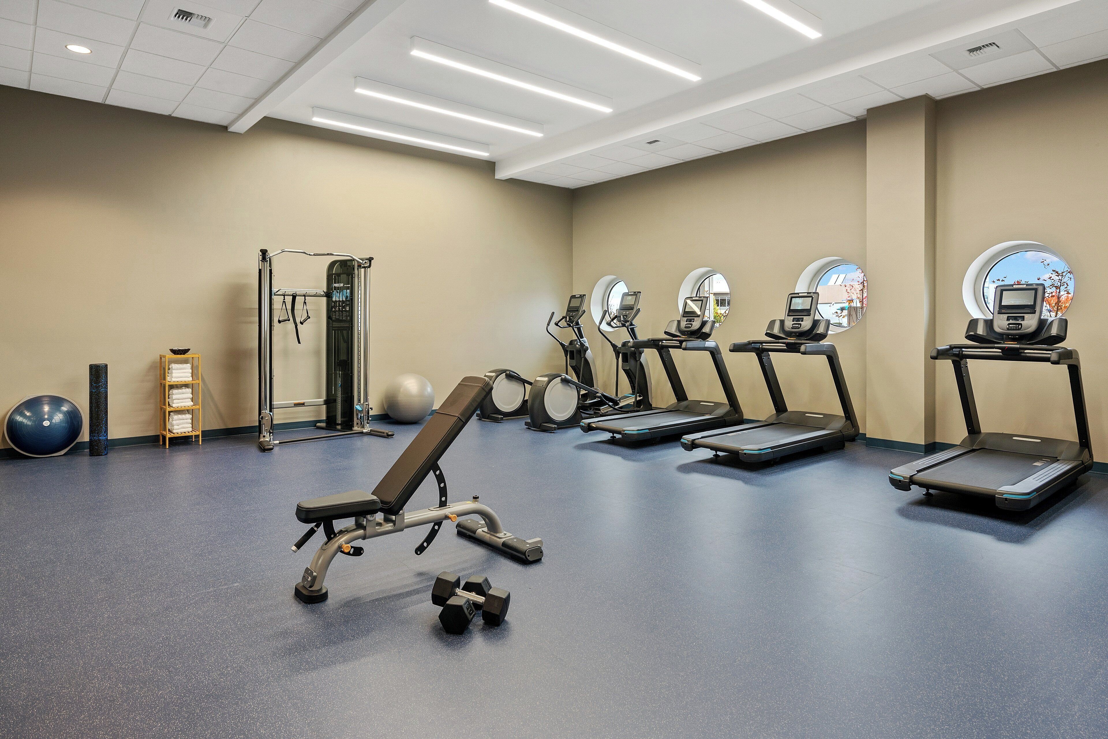 A gym with exercise equipment, including treadmills, a bench, and weights.