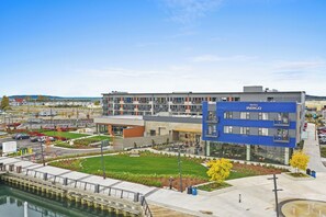 A modern hotel with a blue facade, a courtyard with outdoor seating, and a view of the water. - Hotel Indigo Everett - Waterfront Place by IHG (Everett)