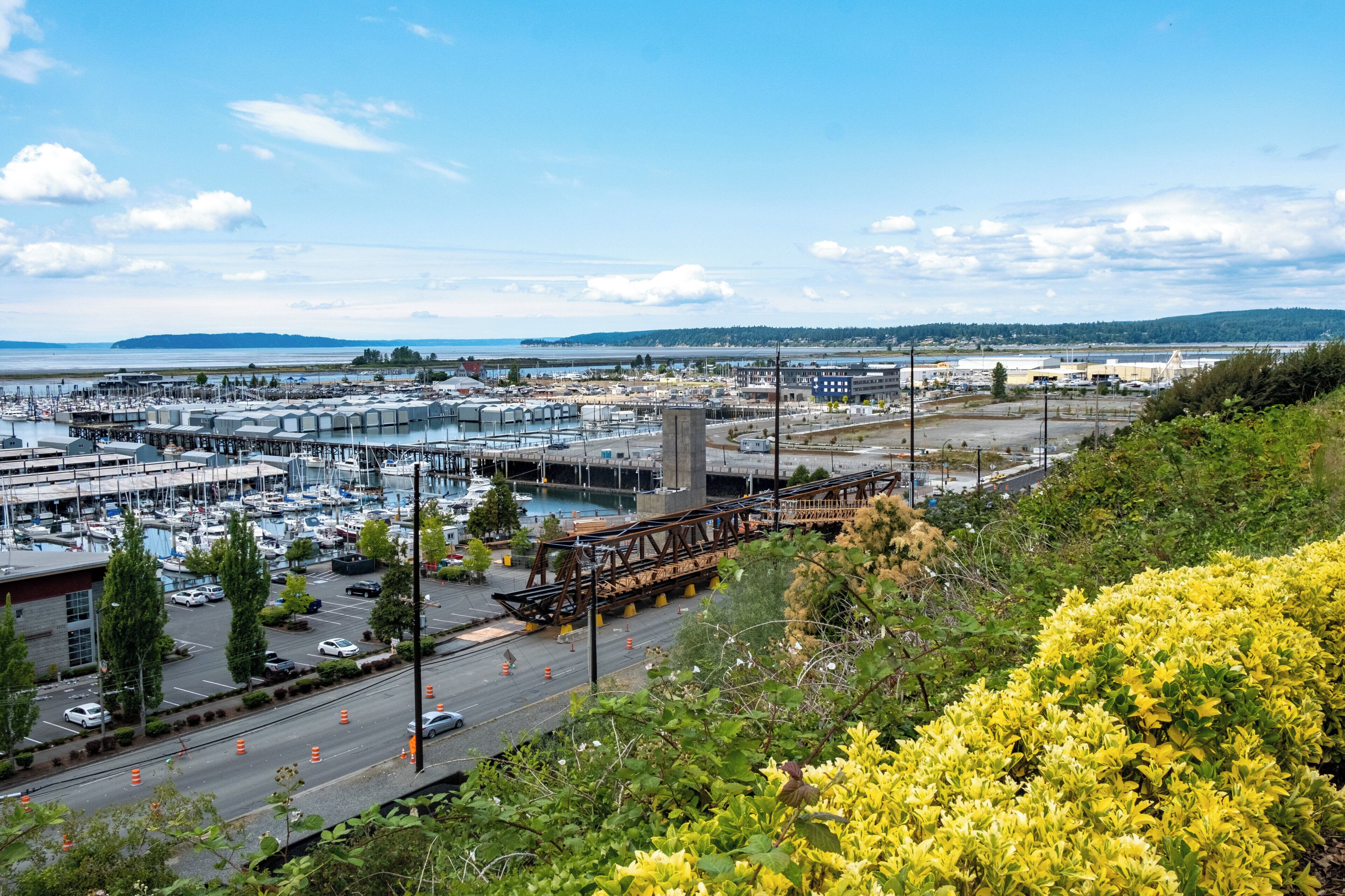A marina with boats, a bridge, and industrial buildings.