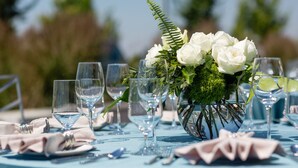 A table set for a formal event with clear glassware and a centerpiece of white flowers and greenery. - Hotel Indigo Everett - Waterfront Place by IHG (Everett)