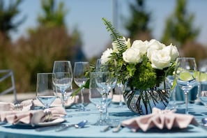 A table set for a formal event with clear glassware and a centerpiece of white flowers and greenery. - Hotel Indigo Everett - Waterfront Place by IHG (Everett)