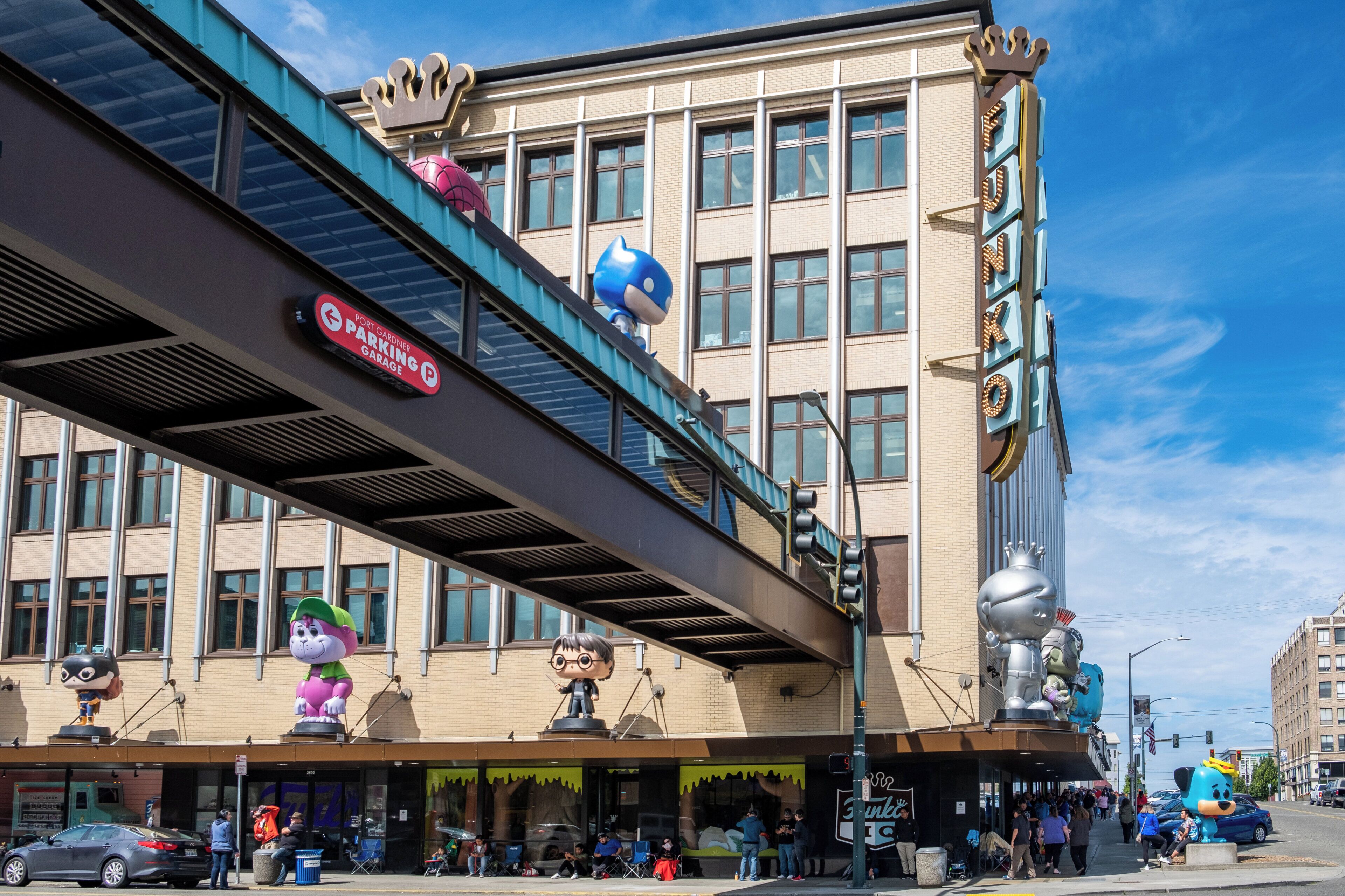 Un edificio con un letrero para un estacionamiento, un puente peatonal y varias estatuas.