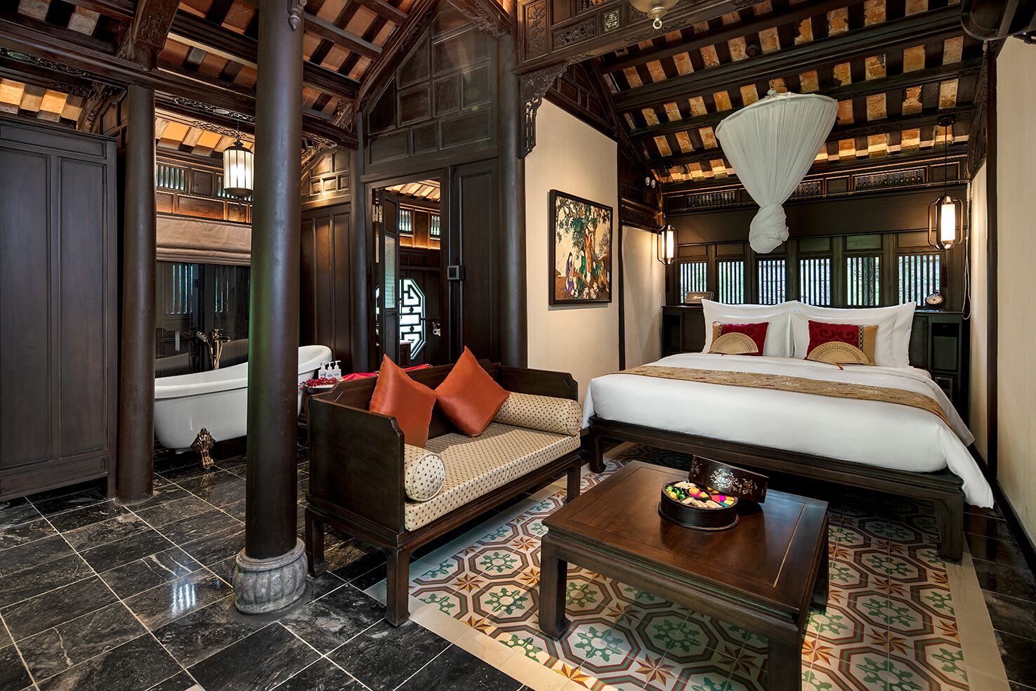 Een klassieke kamer met een bed, bank en een klein tafeltje.