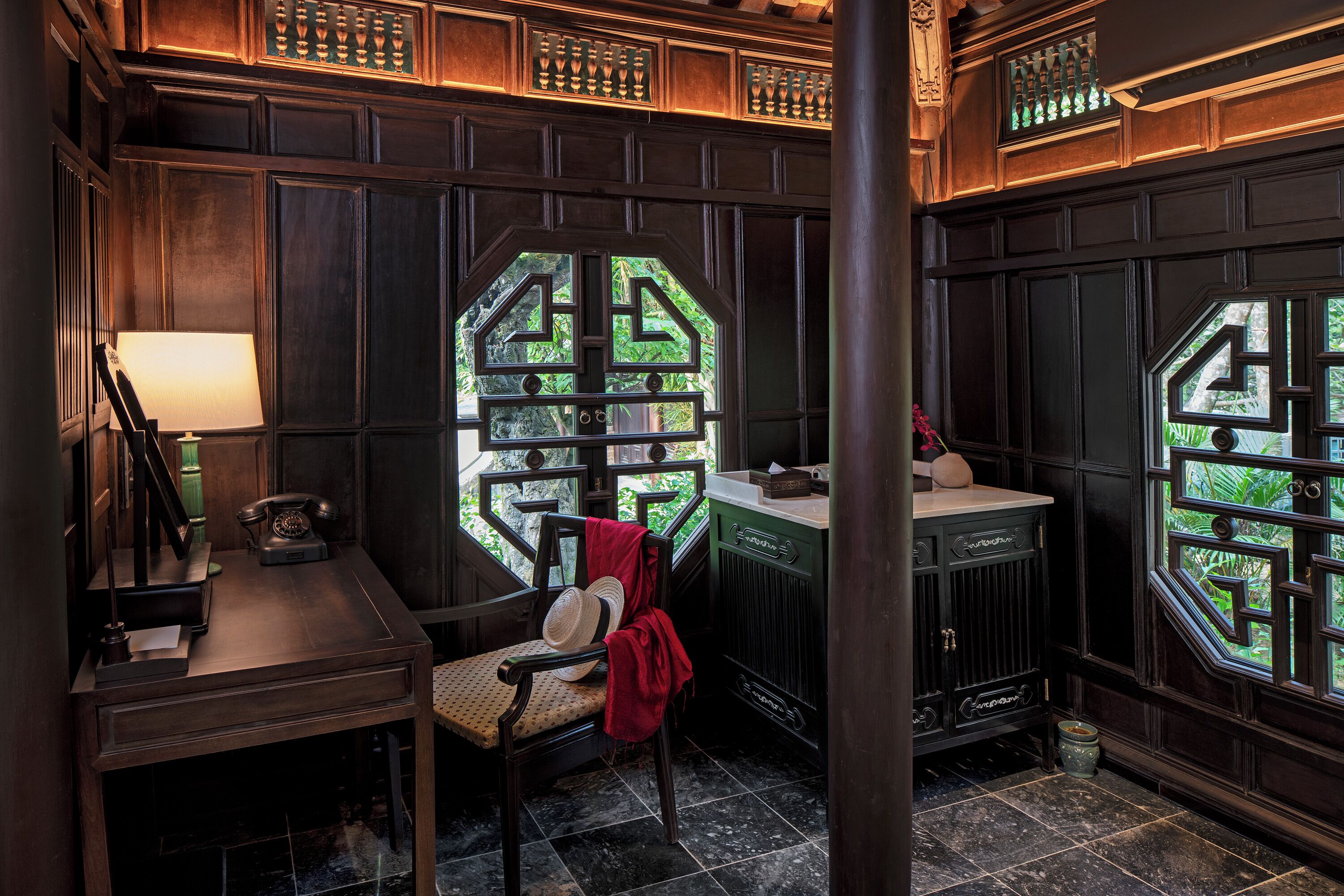 Une pièce comprenant un bureau, une chaise et une grande fenêtre ornée d’un motif géométrique.