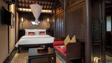 A traditional room with a bed, a sofa, a coffee table, and a decorative wall panel.