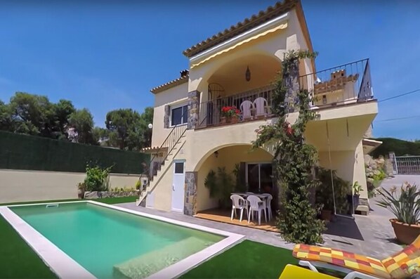 A two-story house with a swimming pool, outdoor seating, and a balcony with plants. - Club Villamar - Cozy villa with saltwater pool and panoramic views (Calonge)