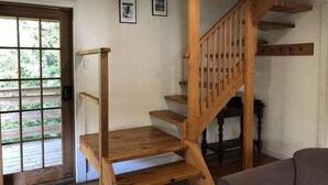 A wooden staircase leading to an upper floor, a door with a view of greenery outside, and a wall with two framed pictures. - Corinna Wilderness Village (Corinna)