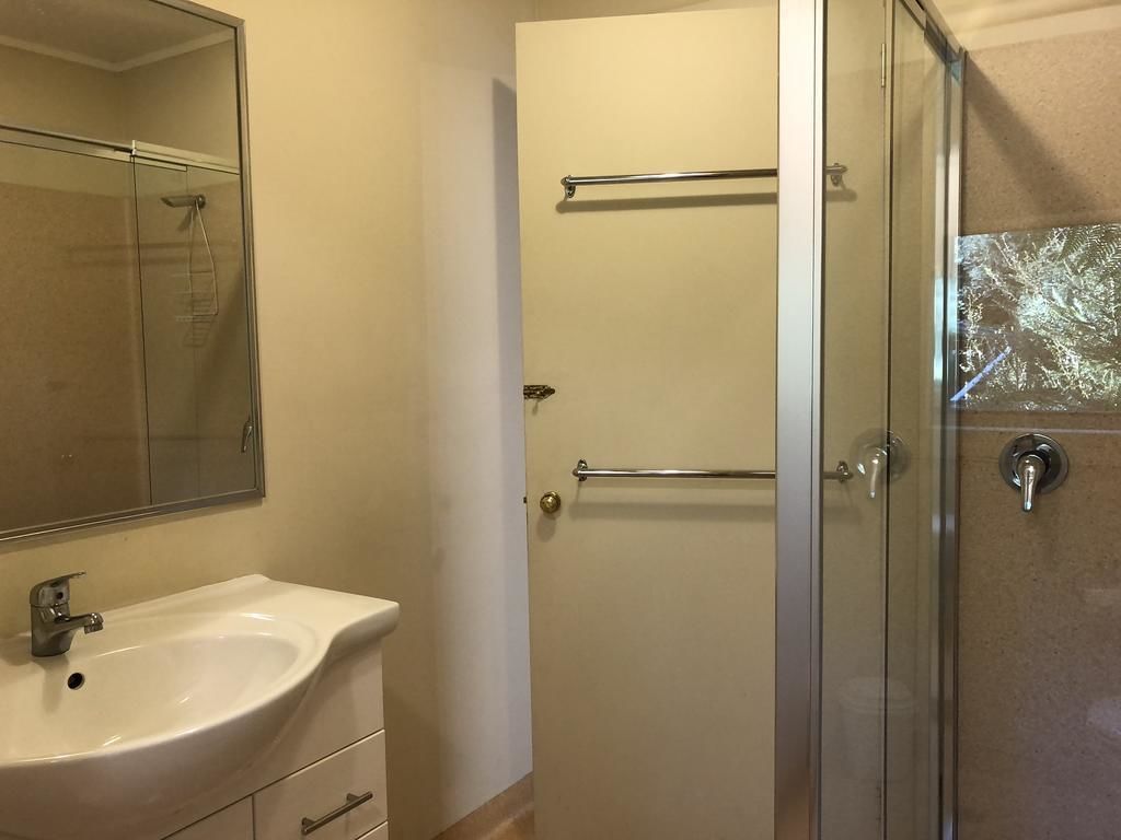 A bathroom with a white sink, a glass shower enclosure, and a towel rack.