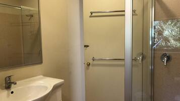 A bathroom with a white sink, a glass shower enclosure, and a towel rack.