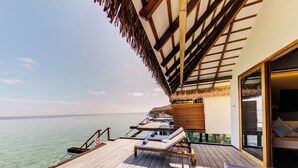 A wooden deck with lounge chairs and a glass door leading to a room. - Cinnamon Velifushi Maldives (Aarah)