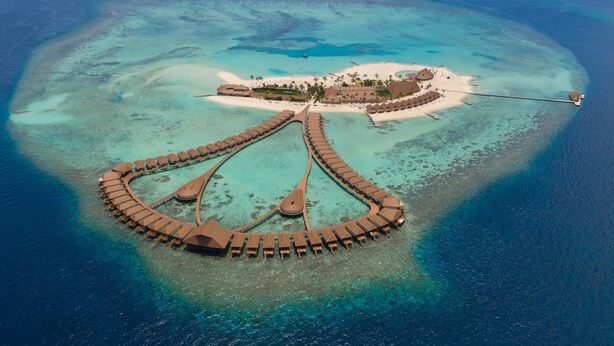 An aerial view of a resort with a crescent-shaped overwater structure, a central building, and a beach area. - Cinnamon Velifushi Maldives (Aarah)
