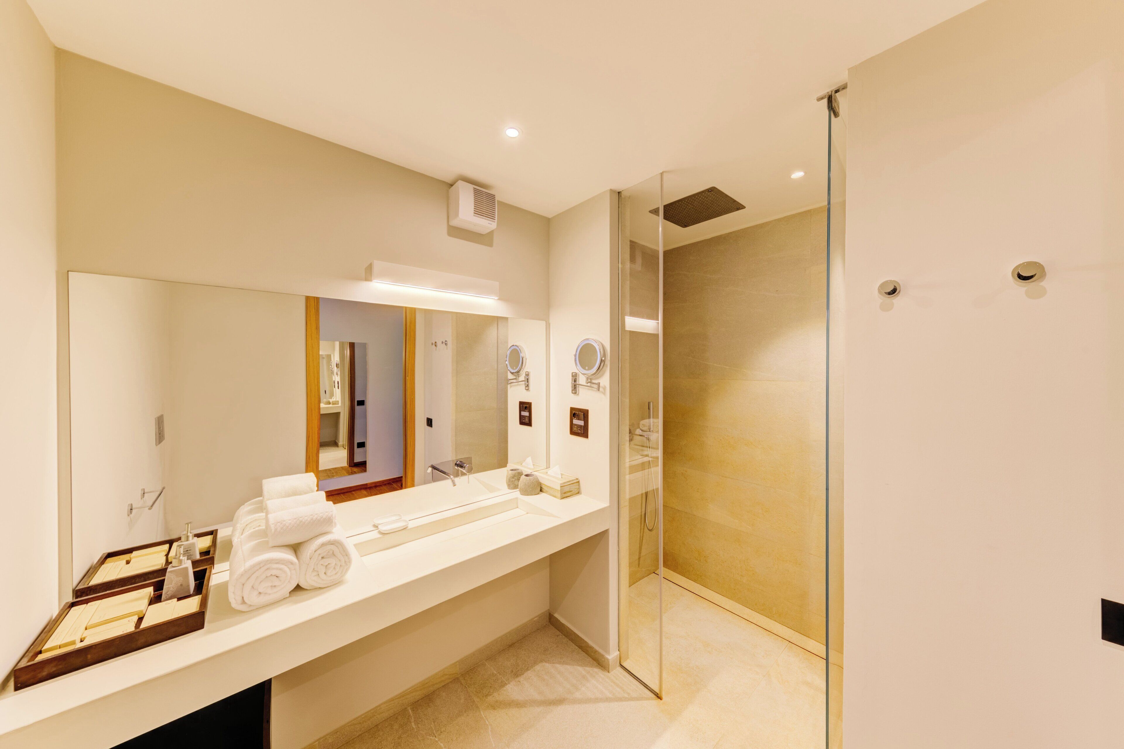 A modern bathroom with a large mirror, a sink, and a glass-enclosed shower.