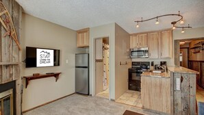 A compact kitchen with a refrigerator, microwave, stove, and a small island with a sink.