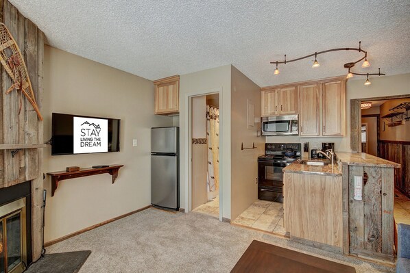 A compact kitchen with a refrigerator, microwave, stove, and a small island with a sink.