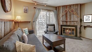 A cozy living room with a fireplace, a sofa, a coffee table, and a clock on the wall.