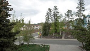 A residential street with houses, trees, and a grassy area.