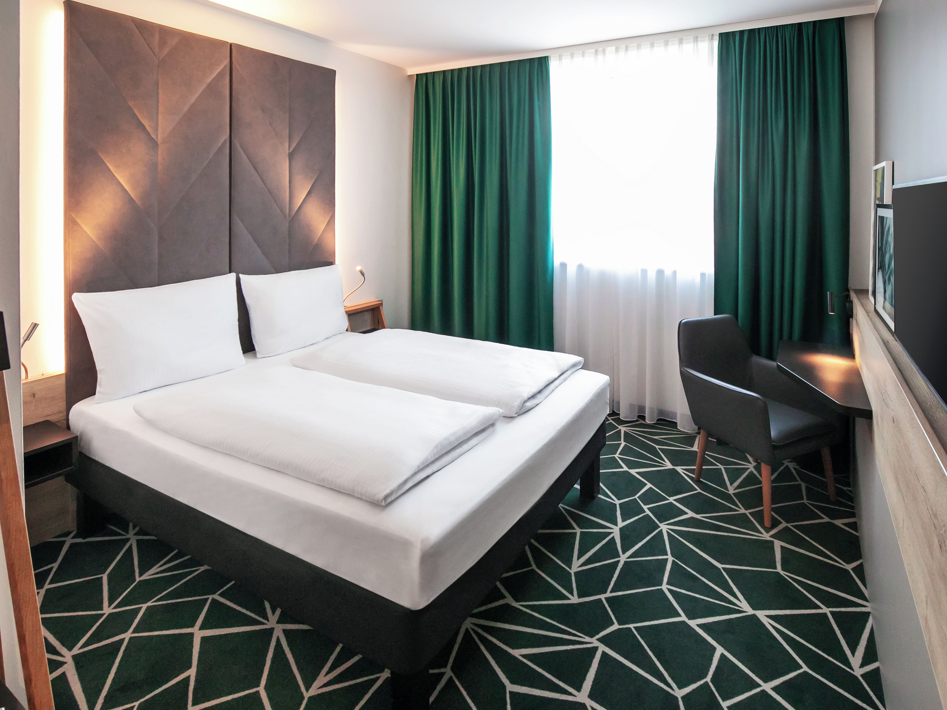 Una habitación de hotel con una cama doble, un escritorio y una silla.