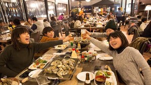 A restaurant with multiple tables, various dishes, and condiments. - Sea Aiga Kaigetsu (Sumoto)