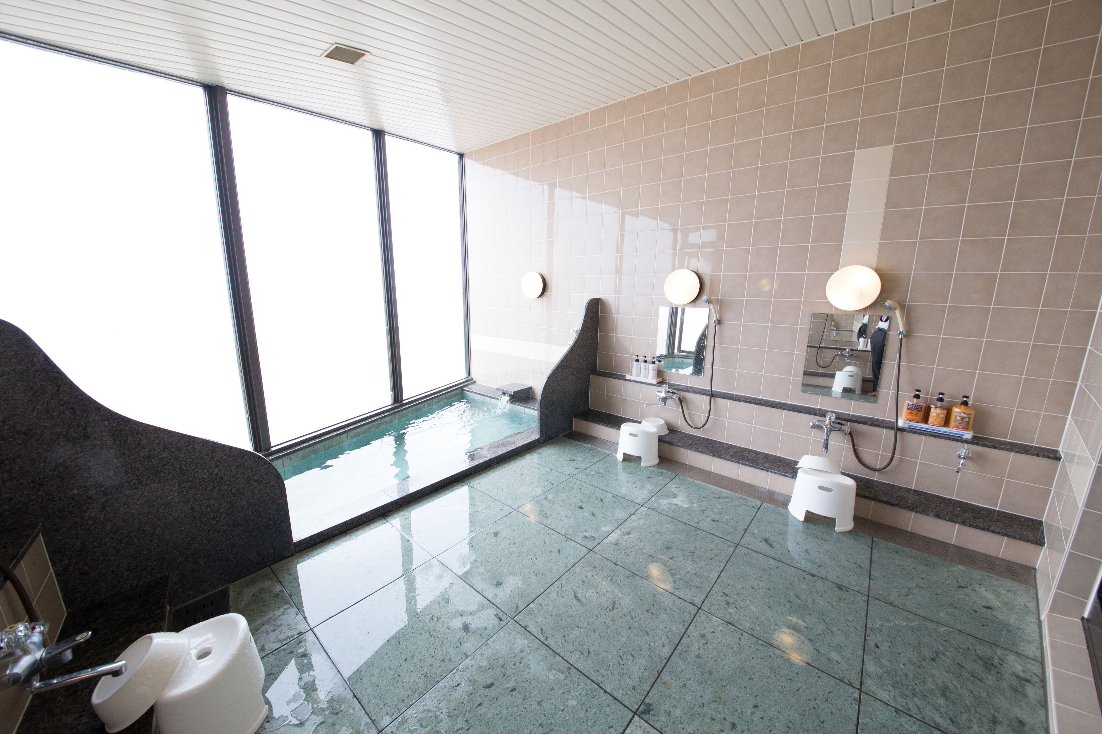 A modern bathroom with a large window, a bathtub, a toilet, and a sink.