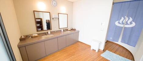 A bathroom with wooden flooring, a sink, a mirror, and a towel rack.