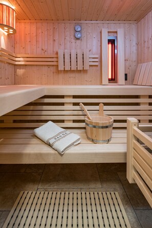 Una sauna con bancos de madera, una toalla y un cubo de madera.