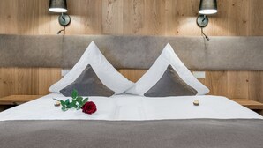 Un lit bien fait, avec deux oreillers, une rose rouge et un petit bol de crème sur la table de chevet.