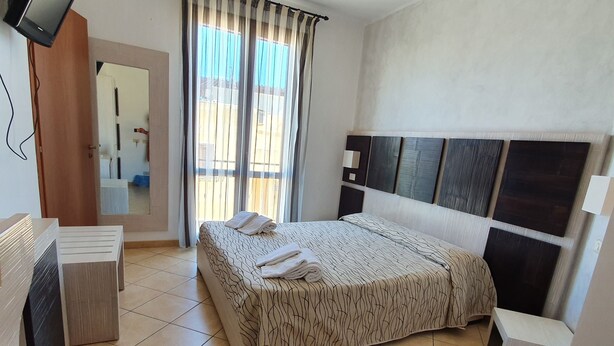 Ein Hotelzimmer mit Bett, Schreibtisch, Spiegel und Fernseher.