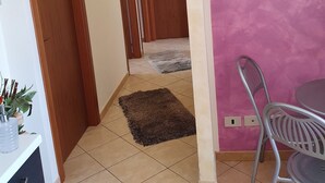 Ein Flur mit Holztüren, ein Essbereich mit einem Metallstuhl und Tisch sowie ein Gemälde an der Wand.