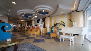 A hotel lobby with a checkered floor, a grand piano, a reception desk, and a large blue sculpture. - Hotel Gradisca (Rimini)