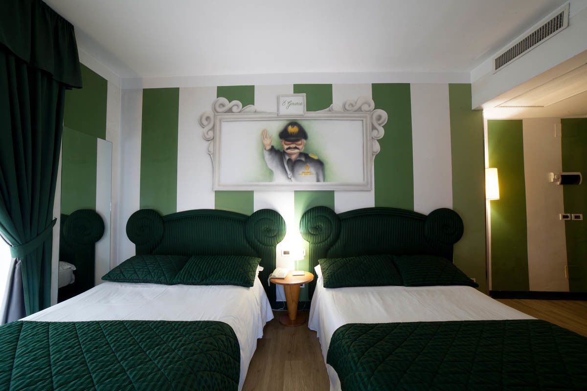 Habitación de hotel con dos camas, una mesita, una lámpara y un cuadro en la pared.