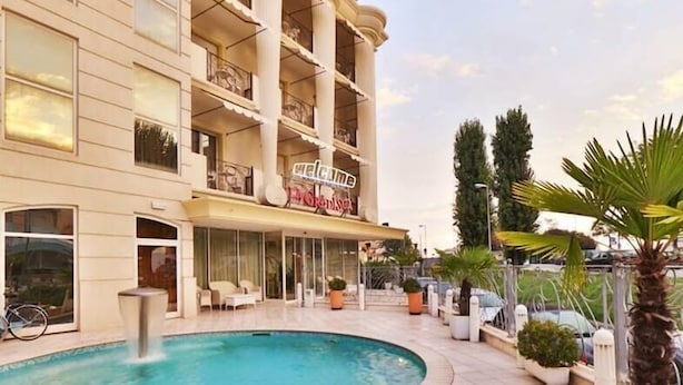 A hotel with a swimming pool, outdoor seating, and a 'Welcome' sign. - Hotel Gradisca (Rimini)