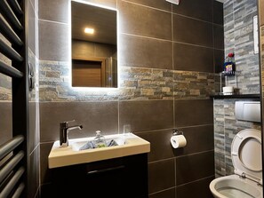 Un baño moderno con lavamanos, espejo e inodoro.