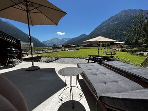 Un patio con mobiliario exterior, una parrilla y vistas a las montañas.
