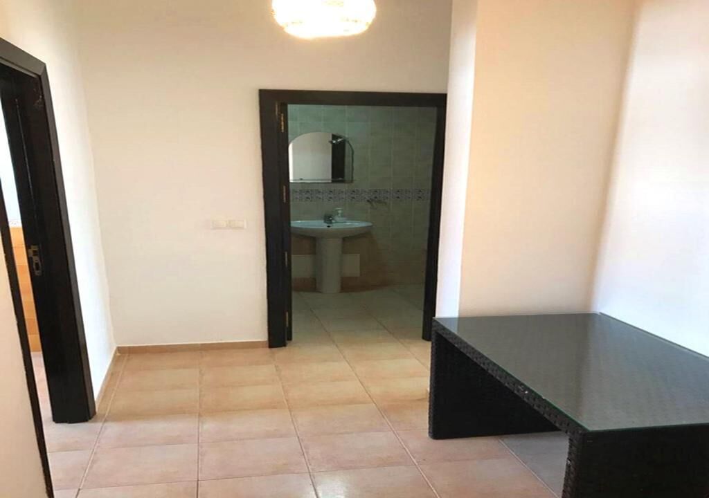 Un couloir menant à une salle de bain équipée d’un lavabo et d’un miroir.