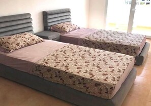 A room with two beds, each with a grey headboard and floral-patterned bedding.