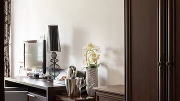 A room with a desk, a lamp, a vase with flowers, and a cabinet.