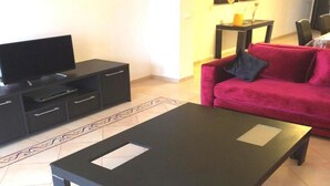 A living room with a black entertainment unit, a red sofa, and a black coffee table. - Residence Marina Saidia 4239 (Saidia)