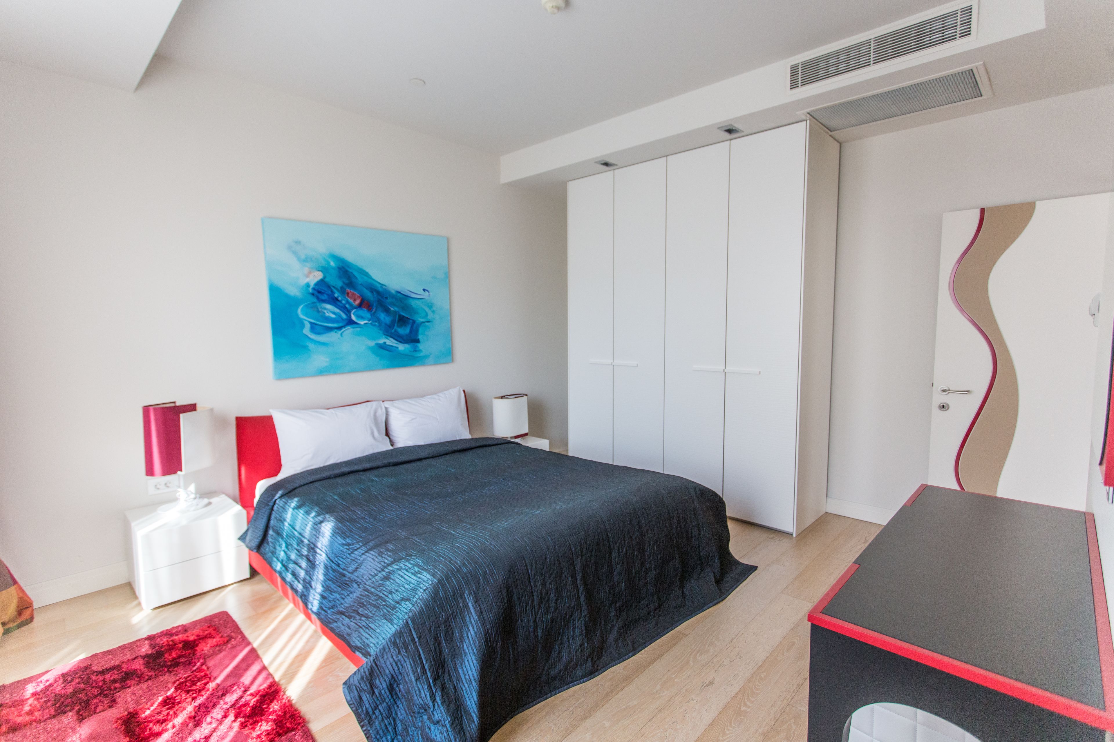 Une chambre à coucher avec un lit, un bureau, une armoire et un tableau au mur.