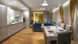 A modern kitchen with built-in appliances, a dining area with a table set for four, and a living area with a sofa and curtains. - Armoni Residence (Istanbul)