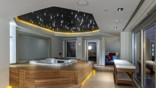 A modern spa area with a wooden hot tub, a bench, and a ceiling with a unique light fixture. - Armoni Residence (Istanbul)