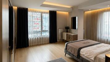A modern hotel room with a large bed, a bedside table, a dresser, and a window with curtains.