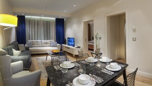A modern living room with a sofa, dining table set for four, and a television. - Armoni Residence (Istanbul)