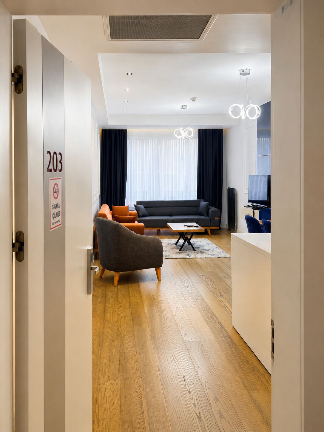A modern hotel room with a sofa, armchair, and a small table.