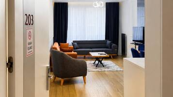 A modern hotel room with a sofa, armchair, and a small table.